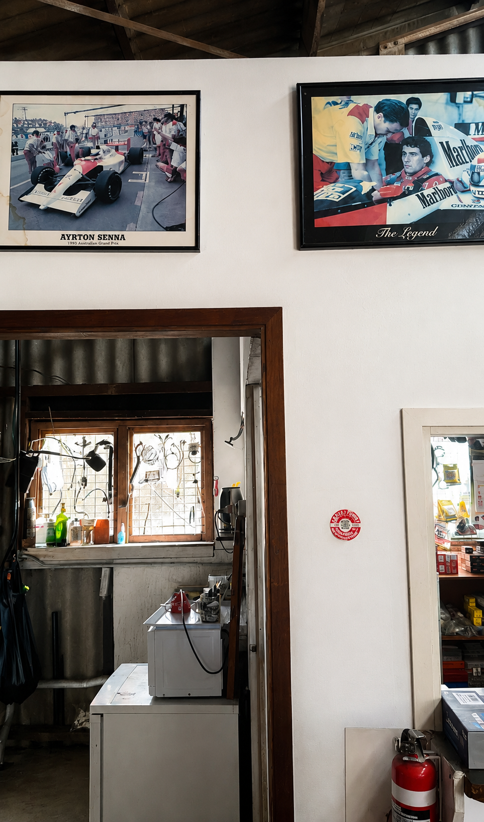 Framed Ayrton Senna Formula One photographs displayed on a workshop wall.